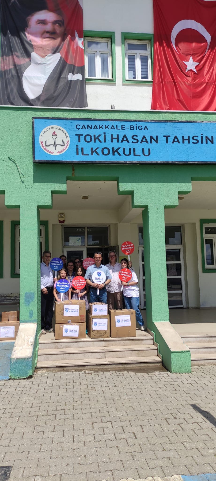 Okula ulaştırılan oyuncak kolileri ve “Gönüllü Ol, Harekete Geç!” yazılı el kartları
